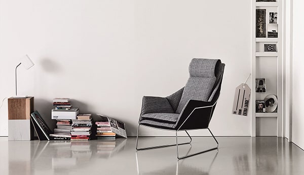 A gray chair next to stacks of books on the floor