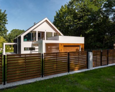 Spacious white house with wooden decoration on garage and wood style fence